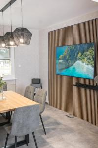 朗斯多夫Triumph Inn Ferienhaus的一间设有桌子的用餐室和墙上的电视