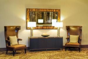 雷丁瑞丁希尔顿逸林酒店的大堂设有两把椅子、一张桌子和一面镜子