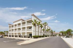 圣奥古斯丁圣奥古斯丁- 维拉诺海滩汉普顿酒店的一条白色的大建筑,在街上种有棕榈树