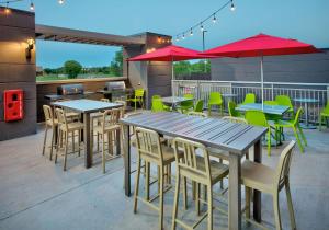 威奇托福尔斯Home2 Suites By Hilton Wichita Falls, Tx的一个带桌椅和红色遮阳伞的庭院