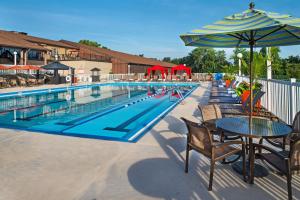 切斯特菲尔德圣路易斯希尔顿逸林酒店 - 切斯特菲尔德的一个带桌椅的游泳池以及遮阳伞