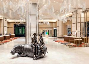 拉斯维加斯Crockfords Las Vegas, LXR Hotels & Resorts at Resorts World的坐在大堂的狗上的一个女人的雕像