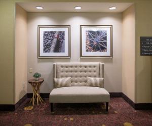 本顿维尔Hilton Garden Inn Bentonville Rogers的一张椅子,放在一个等候室,墙上有两张照片