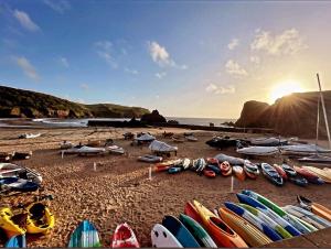 瑟勒斯通9 The Downs, Thurlestone, South Devon on the coastal footpath overlooking Burgh Island的海滩上的冲浪板和船只