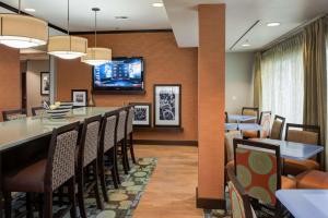 塔尔萨塔尔萨沙泉汉普顿酒店的一间设有酒吧的用餐室和一台墙上的电视