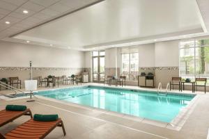 伍斯特Homewood Suites By Hilton Worcester的游泳池位于酒店客房内,配有桌椅