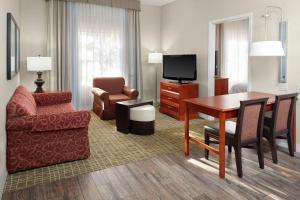 塔拉哈西霍姆伍德希尔顿套房酒店的客厅配有桌子、椅子和电视