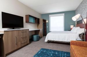 罗斯威尔Home2 Suites By Hilton Roswell, Ga的一间卧室配有一张床和一台平面电视