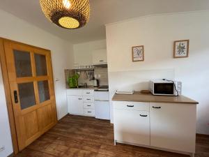 卡什佩尔斯凯霍里Apartment Brusinka的厨房配有白色橱柜和台面上的微波炉