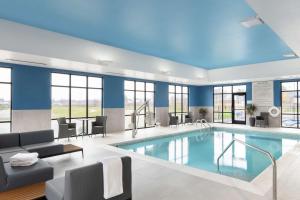 奥法伦Hampton Inn O'Fallon, Il的游泳池位于酒店带蓝色墙壁和窗户的客房