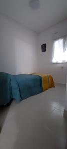 皮尔托贝加LA CASITA SERRANA的白色客房的一张床位,配有蓝色和黄色的毯子