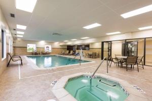 休伦港休伦港希尔顿恒庭酒店的一个带热水浴缸和桌椅的大型游泳池