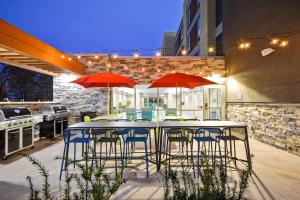 莫米Home2 Suites By Hilton Maumee Toledo的一个带桌椅和红色遮阳伞的庭院