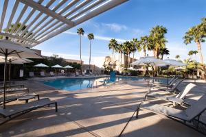 土桑图森希尔顿逸林酒店 - 里德公园的一个带白色椅子和遮阳伞的游泳池,并种植了棕榈树