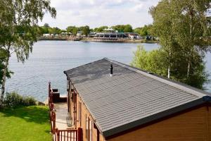 塔特舍尔Fable Lodge Tattershall Lakes - luxury lakeside lodge with hot tub的湖上的一个码头,有房子