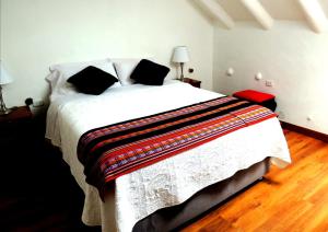 库斯科科里宝石旅馆的卧室配有一张带黑色枕头的大型白色床。