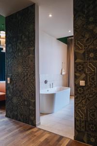 兰茨胡特Hotel Amalia - Boutique Hotel的带浴缸的浴室和带图案墙的墙壁