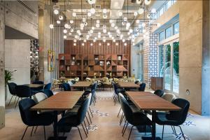 迈阿密Atwell Suites - Miami Brickell, an IHG Hotel的餐厅设有木桌、椅子和吊灯。