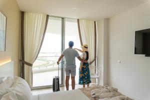 普拉亚斯Karibao Resort Town的男人和女人看着酒店房间的窗户