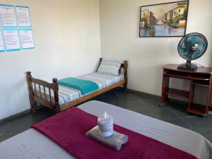 瓜拉派瑞Hope Hostel Guarapari的客房设有两张床和一张带风扇的桌子。