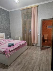 茨卡尔图博Magdan house的一间卧室配有一张带粉红色棉被的床