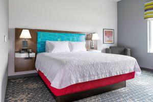 新斯坦顿Hampton Inn & Suites Pittsburgh New Stanton PA的酒店客房带一张大床和一把椅子
