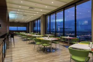 波哥大波哥大机场希尔顿汉普顿酒店的餐厅设有桌椅和大窗户。