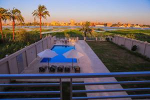 卢克索Royal Nile Villas - Nile View Apartment 1的享有带遮阳伞和椅子的游泳池的景色
