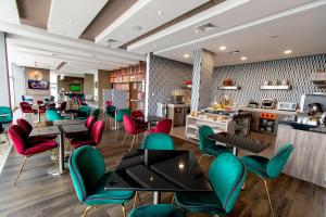 利马Hampton By Hilton Lima San Isidro的餐厅设有绿色和红色的椅子和桌子
