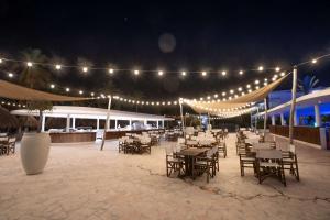 威廉斯塔德Mangrove Beach Corendon Curacao All-Inclusive Resort, Curio的一个带桌椅的庭院,晚上配有灯光