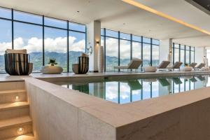圣何塞Hilton San Jose La Sabana的客房设有带椅子和窗户的游泳池。