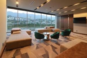 蒙特雷Hilton Garden Inn Monterrey Obispado的客房设有沙发、椅子和大窗户。