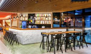 瓜鲁柳斯Hampton by Hilton Guarulhos Airport的酒吧设有木桌和酒吧凳子