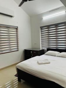 科泽科德Saaketh Holiday Home的一间卧室设有一张大床和两个窗户。