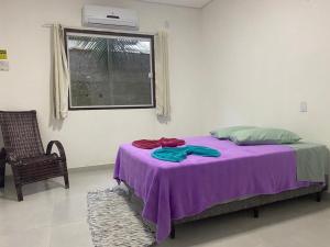 帕拉蒂pousada Cantinho da mata的窗户客房内的一张带紫色毯子的床
