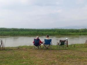 Semliki Fishing River Camp的两个人坐在椅子上,靠水边