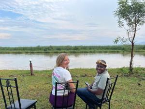 Semliki Fishing River Camp的坐在河边椅子上的男人和女人