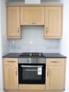 埃普瑟姆Stylish 2 bedroom apartment in the heart of Epsom town centre的厨房配有炉灶和木制橱柜。