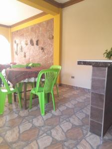 TorotoroHospedaje Matita - Torotoro的一间设有绿色椅子和石墙的用餐室