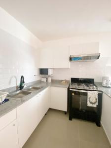 蓬塔卡纳Oasis Punta Cana Apartments 3的厨房配有白色橱柜和黑炉灶烤箱。