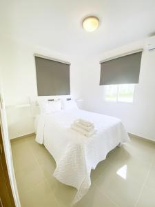 蓬塔卡纳Oasis Punta Cana Apartments 3的白色卧室配有带白色床单的床和2扇窗户