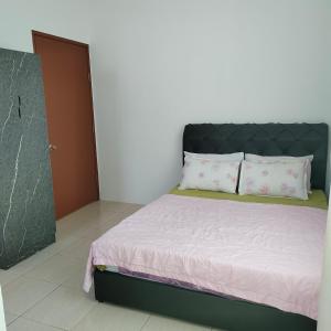 斗湖Ummik Homestay的一间卧室配有一张带黑色床头板和枕头的床。