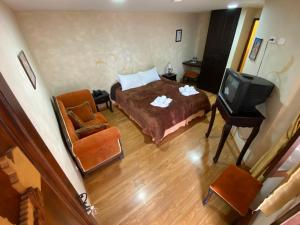 拉塔昆加Golden Rest Ecuador的一间卧室配有一张床、一台电视和一把椅子