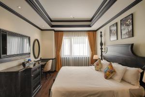 岘港岘港莫纳科酒店的一间卧室配有一张床、一张书桌和一台电视