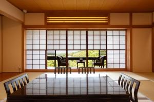 箱根Hakone Ashinoko Bikeikan 箱根芦ノ湖 美景館的客房设有桌椅和大窗户。