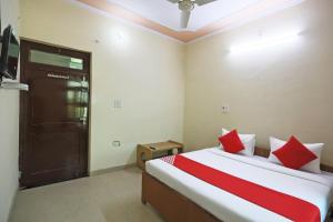 MahendragarhOYO 62761 Hotel Daksh的一间卧室配有红色和白色枕头的床