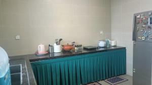 而连突Nurkasih Homestay Jerantut的厨房配有绿色的柜台和冰箱。