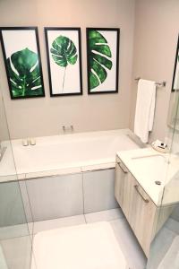 比勒陀利亚Menlyn Trilogy - 2 Bedroom & Great Views - No Loadshedding的带浴缸和水槽的浴室以及框架图片