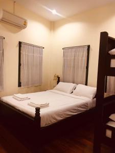 董里Thunyaporn Hostel的一间卧室配有一张带白色床单的床和一扇窗户。