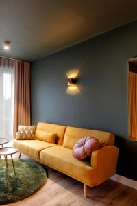 亨厄洛Wapen van Hengelo Residence Suites - digital key by email的客厅里一张黄色的沙发,墙上挂着